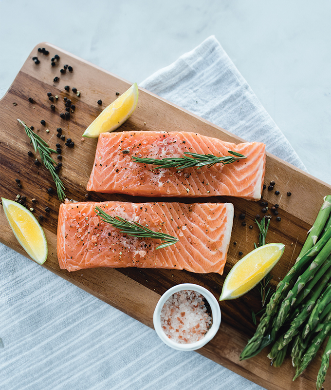 salmon, asparagus, and lemon wedges on a wooden cutting board